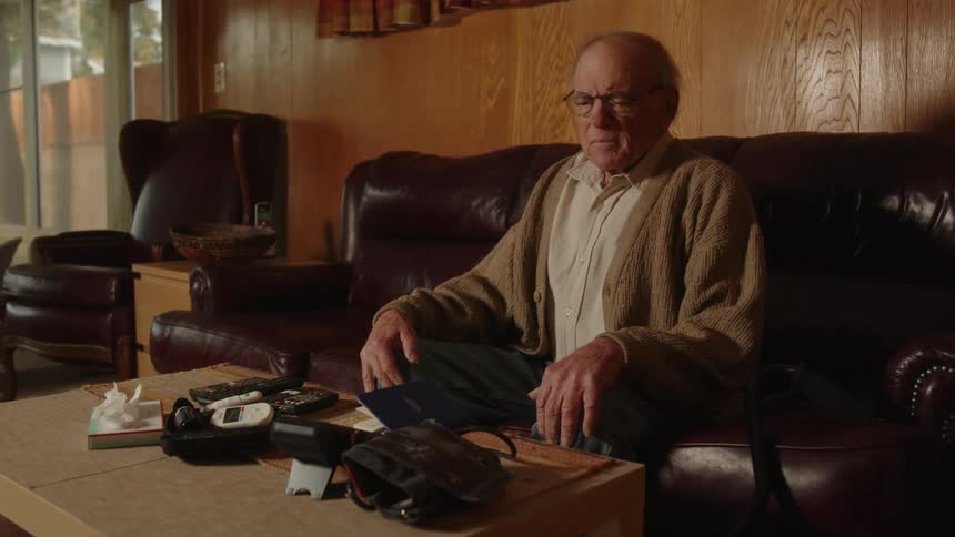 An elderly man sitting on the couch at home feeling uncomfortable