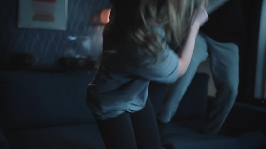 A young couple is having a pillow fight at night time