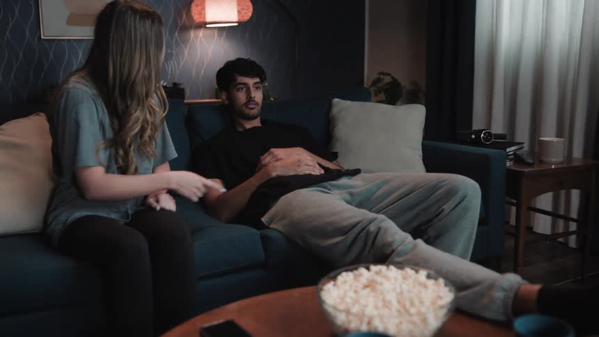 A man has fallen asleep during a movie the girl hes watching with wakes him up