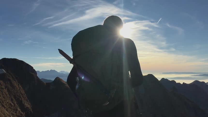 A man is looking at the view from a mountain top