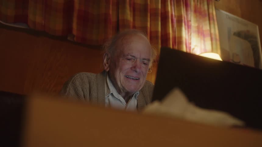 A man smiles while looking at his laptop