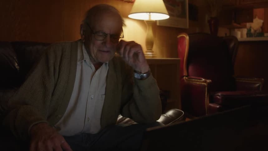 A man smiles while typing on his laptop