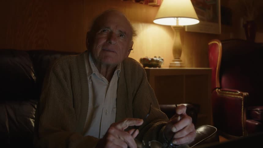 A man sits thinking on his couch