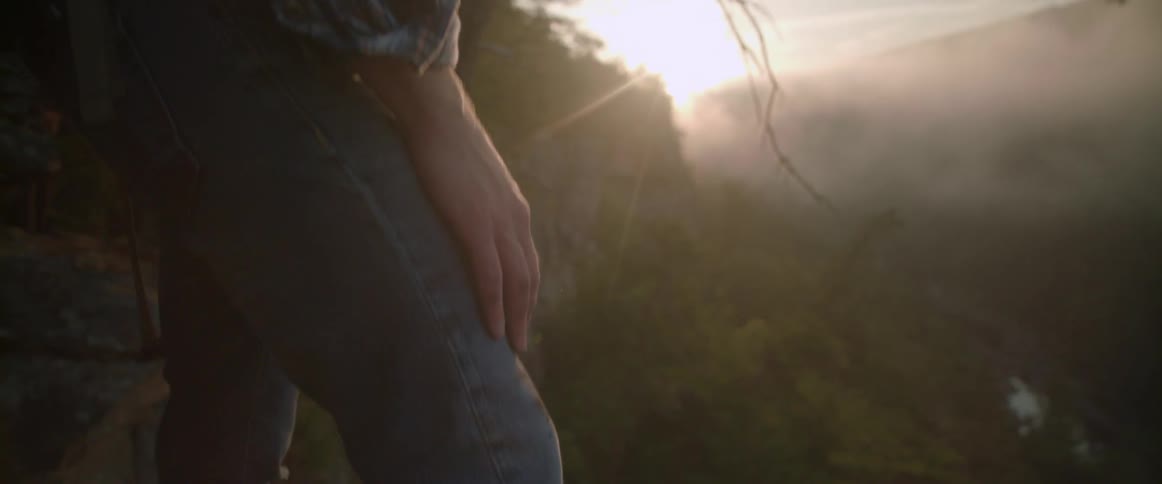 A hiker steps toward a ledge and stops to look at the view