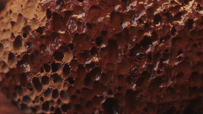 Rain falls and drips down a rock