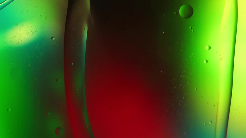 Clear liquid stretches and bubbles move and float as colored lights glow in the distance