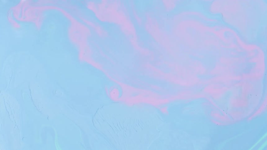 A colorful light blue liquid is poured and swirls around creating many ripples