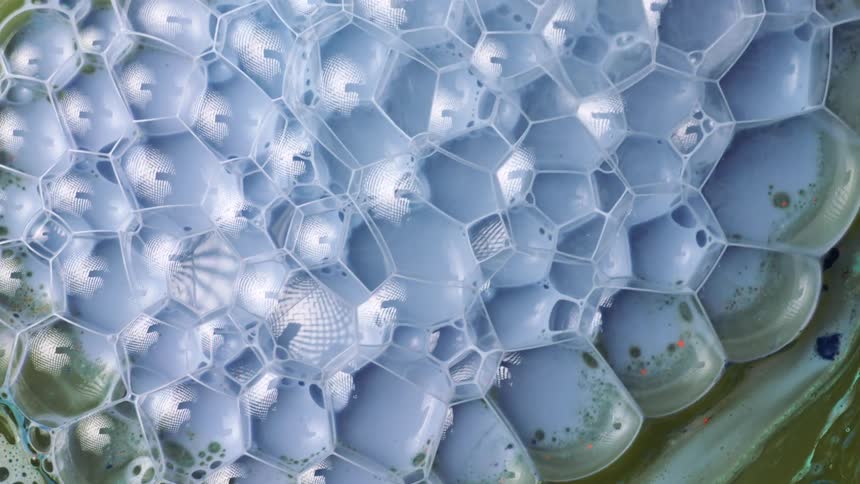 A colorful liquid is poured atop another one and generates a number of bubbles