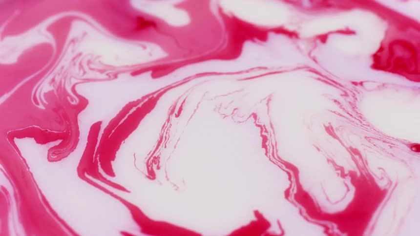 Red and white paints swirl together on surface