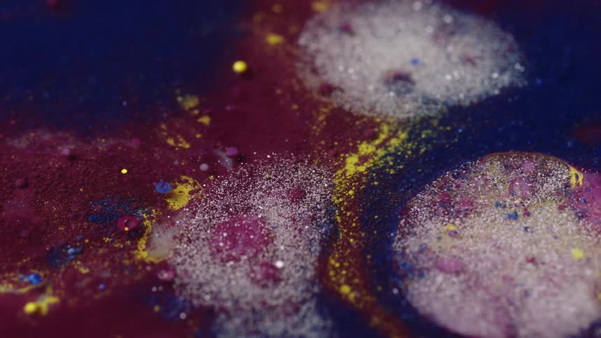 Glitter is poured onto a blue liquid