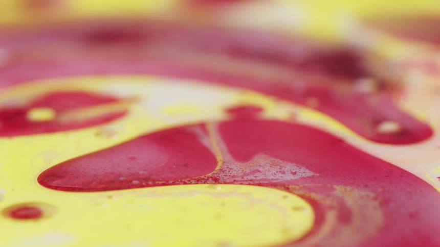Colorful bright red an yellow liquid ink mixing and swirling together