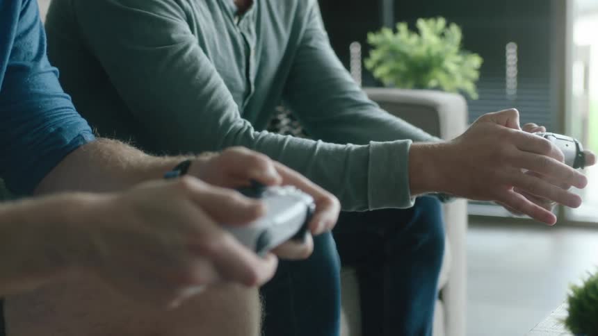 Two men are sitting on the couch playing video games