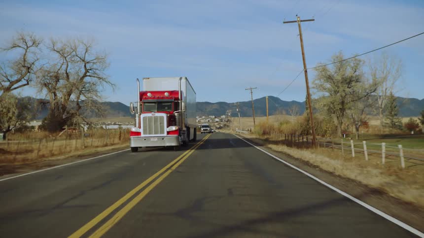 Traffic is driving through a rural area during the day time
