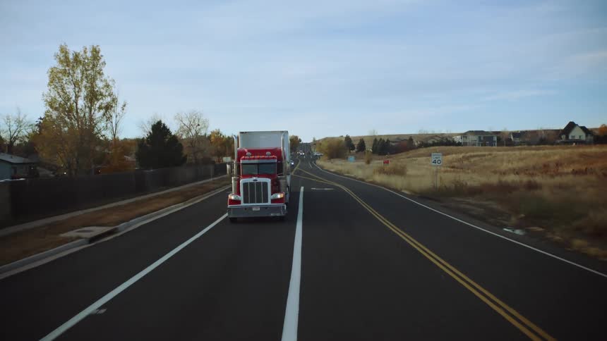 Trucks and cars are driving through a rural area