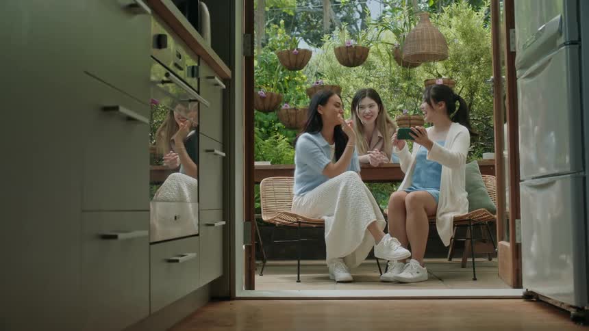 Three women sitting outside smiling and posing for a picture taken by one of the womens phone