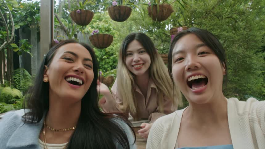 Three women are smiling outdoors together in spring