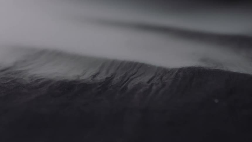 Pale vapor flows across textured dark surface