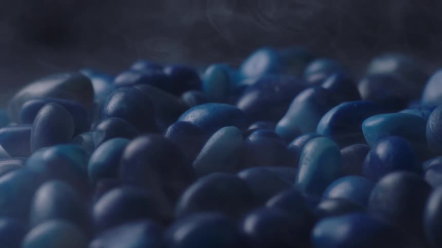 Wisps of mist flow and hover over a large pile of smooth blue stones