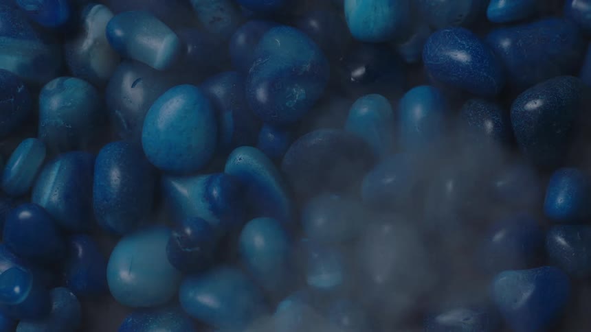 Blue painted stones with smooth edges with mist being sprayed on them