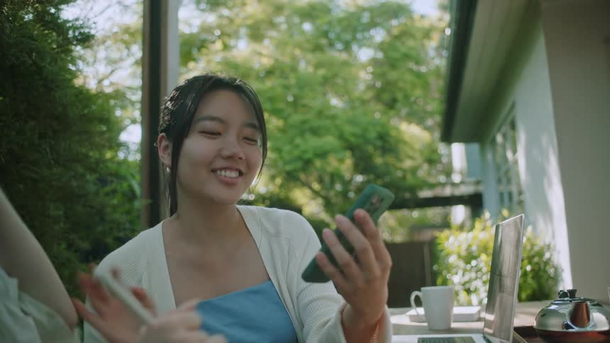 Happy young woman shows a friend a funny message she received on the phone