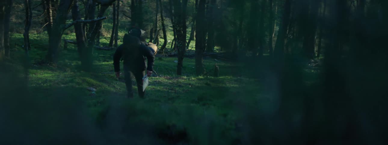 A man is hiking through a forest area during the day time