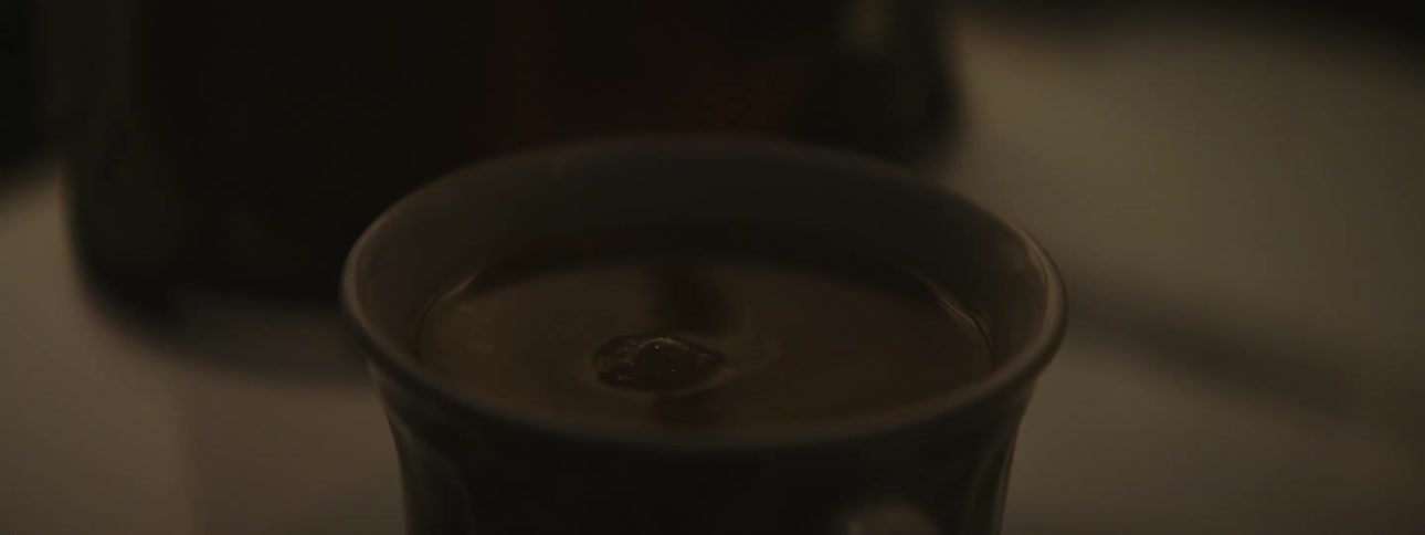 A small glass cup has additional coffee carefully poured into it