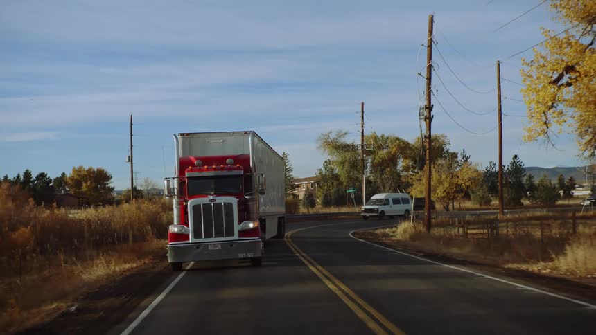 Trucks are driving on a road in a rural area