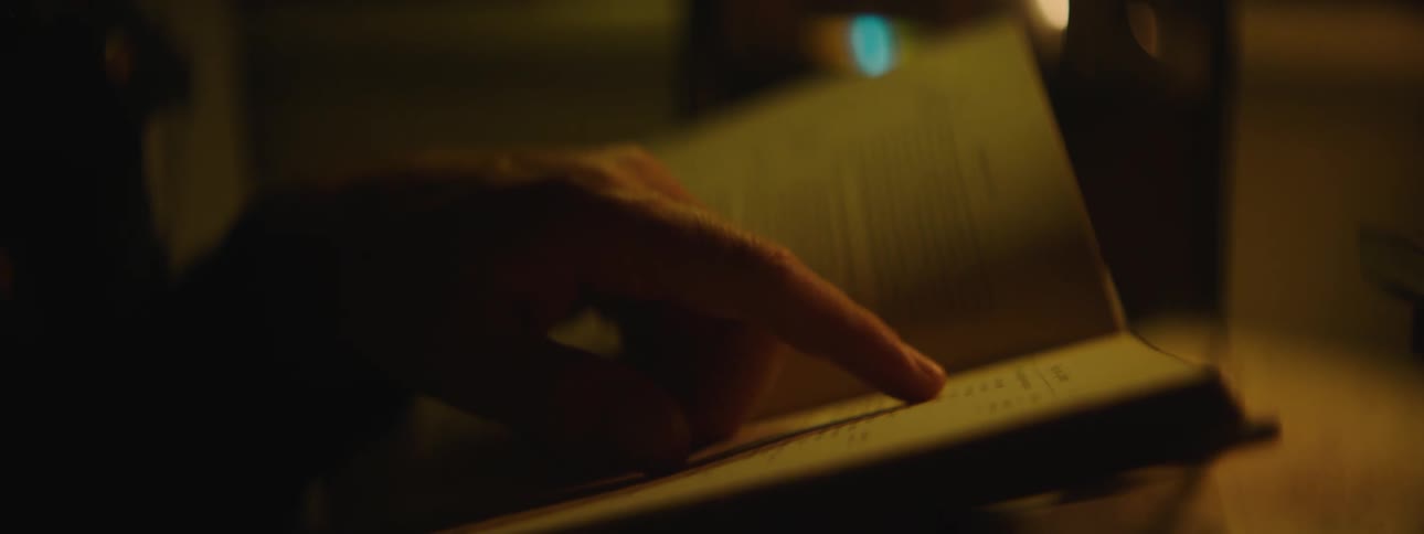 A close up of a persons hand looking through a book and using their finger to go line by line