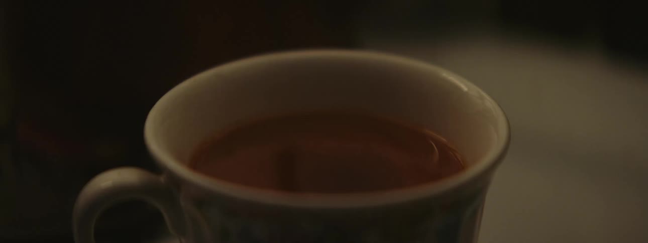 A person pours creamer into coffee and mixes it with a spoon