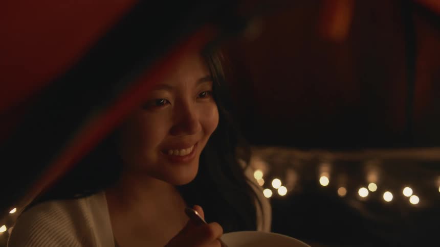 A woman is eating food while camping outdoors