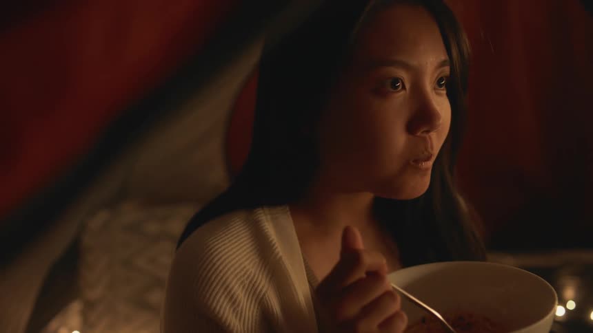 A young woman is eating food indoors