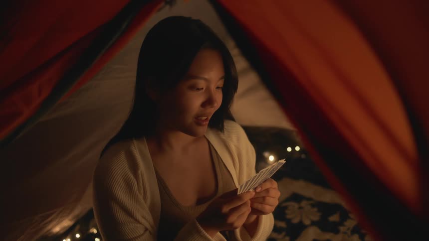 A woman is playing a card game while camping