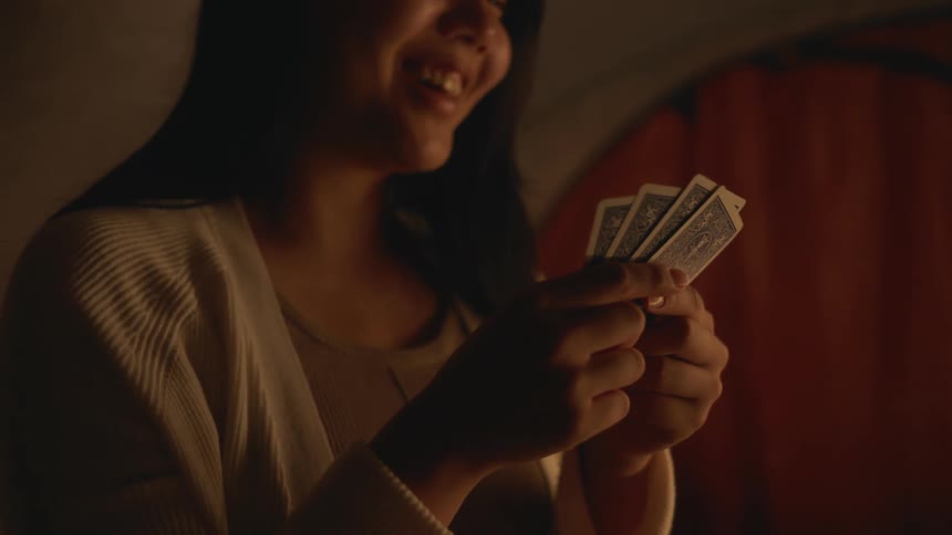 A young woman is playing cards and is in indoors