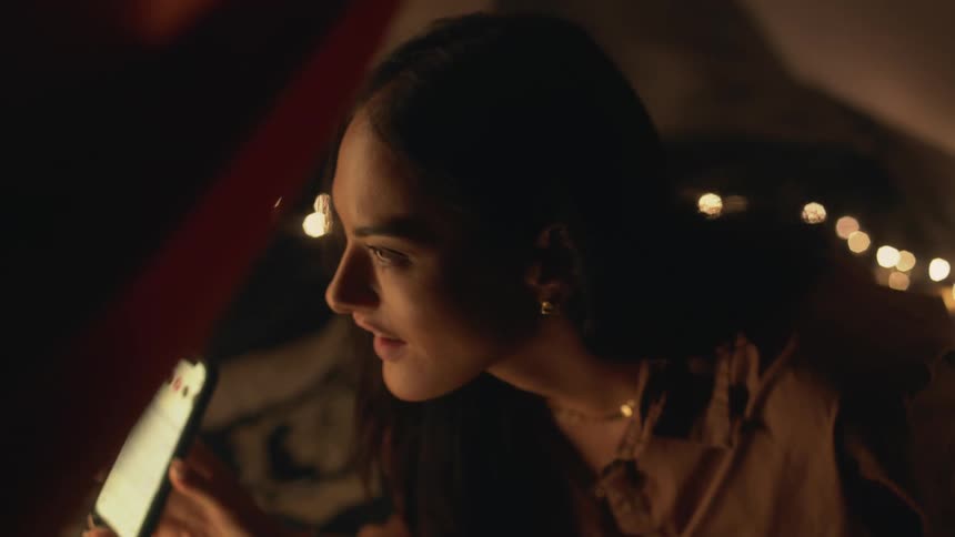 A young woman is inside of a tent and is looking at her phone