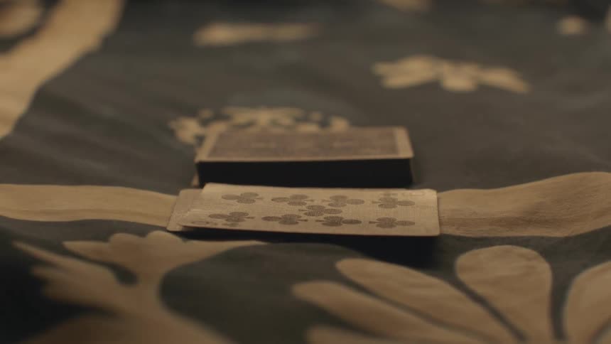 Close up of the hands of a couple of friends playing a simple game of cards over the bed