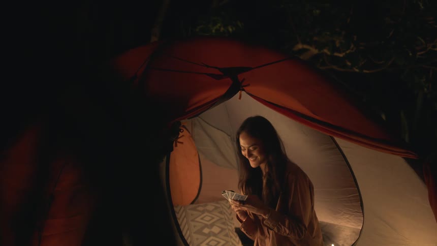A woman is playing a card game while camping