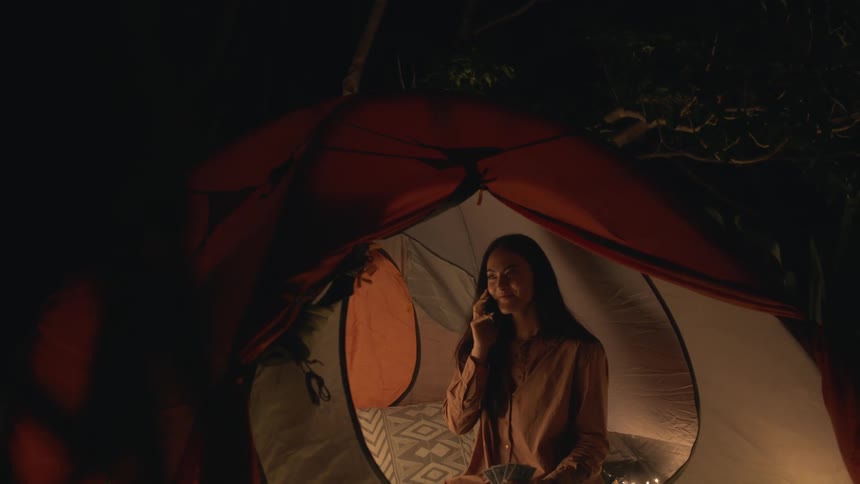 A woman is talking on the phone during camping