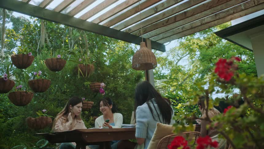 A woman shows her friends her smartphone while sitting on a restaurant patio