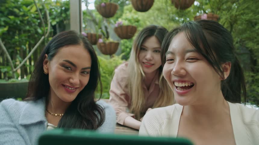 Group of happy friends take selfies with a phone on the garden at daytime