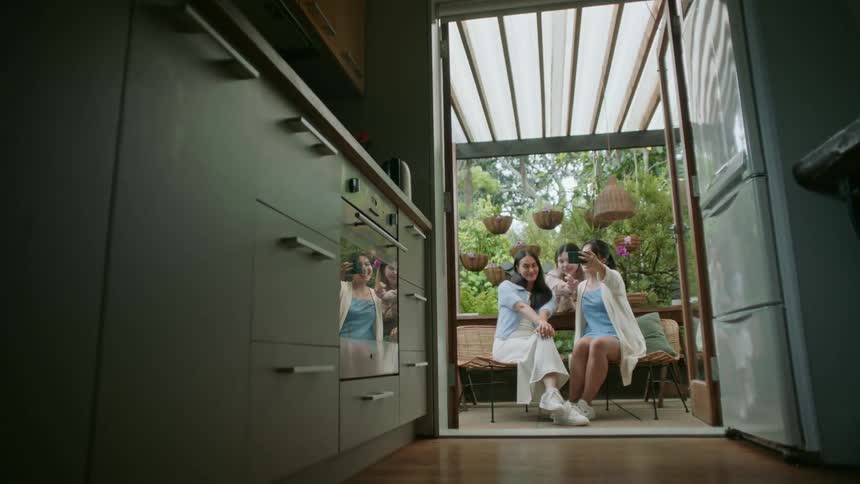 Three young girls sitting together on the patio off the kitchen spending time together and taking a selfie