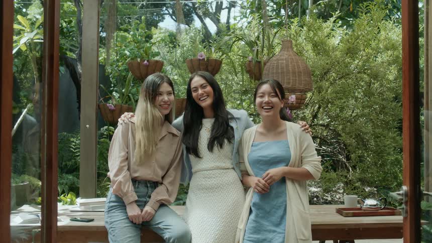Three young women are standing sidebyside and laughing while posing for the camera
