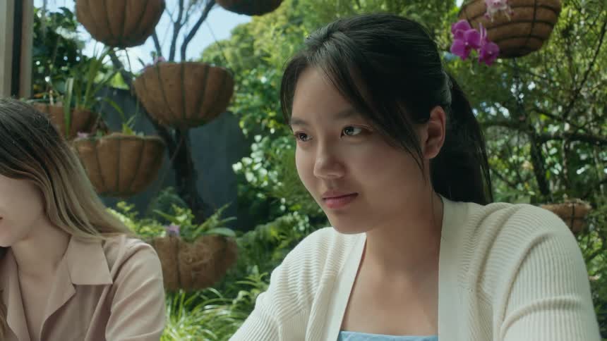 A woman smiles to herself while sitting outside with a friend
