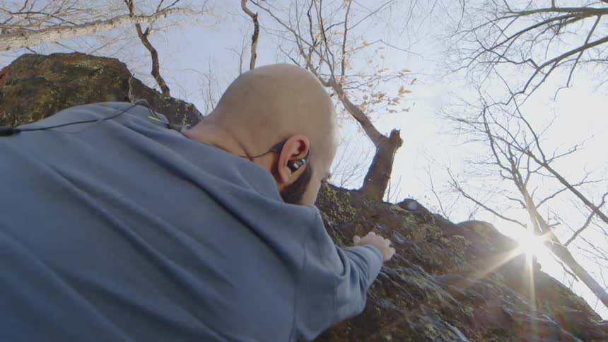 The man is reaching up to begin rock climbing
