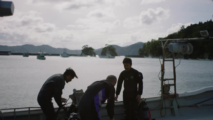 Three men are on a sailboat on a body of water