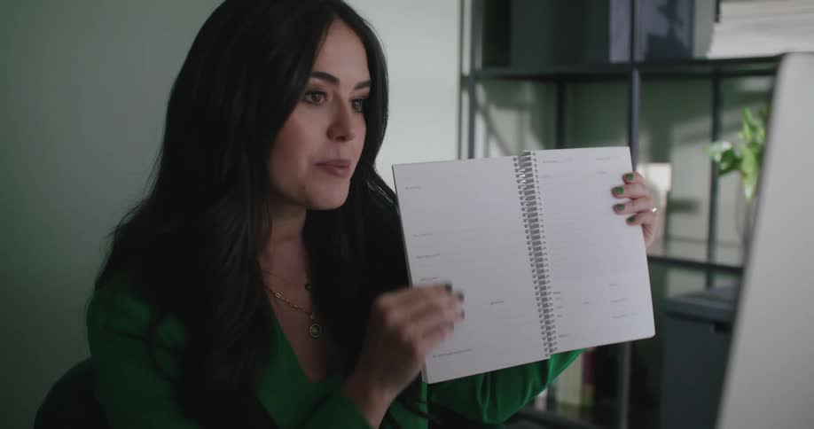 A woman is talking to someone and showing a notebook