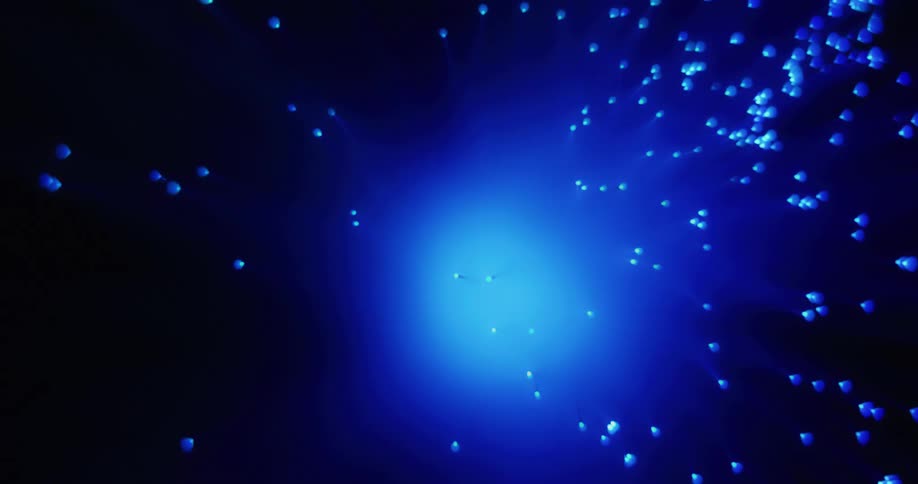A rotating green light glows in the darkness and changes to blue as many small orbs float and move