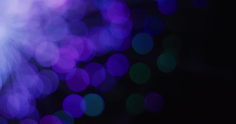 A bright light glows as colored orbs rotate in the darkness