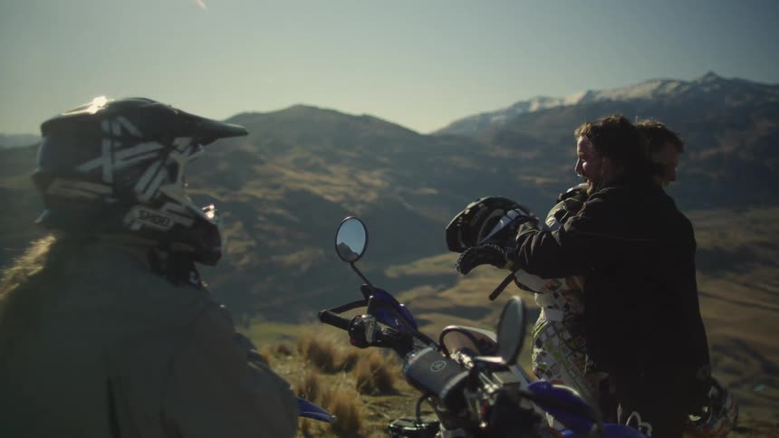 A group of friends are outdoors with their motorcycles