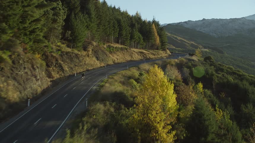 Aerial view of bike riding on mountain highway near woods