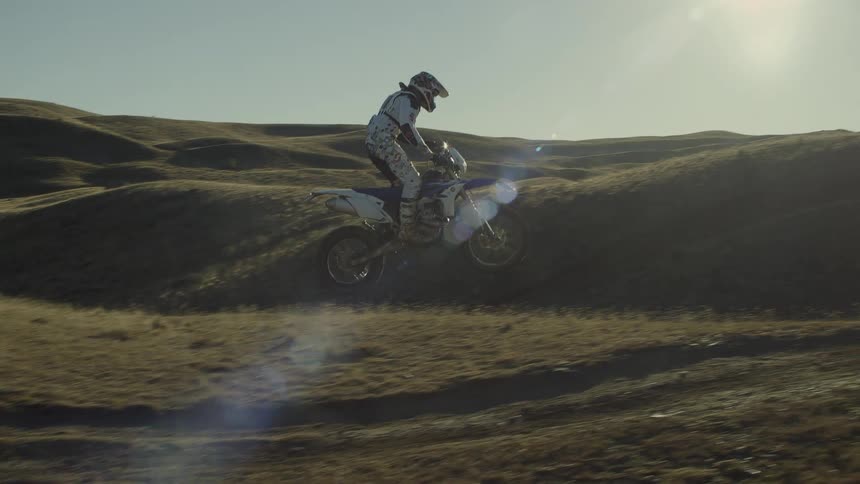 A man is riding a motorcycle outdoors and doing stunts